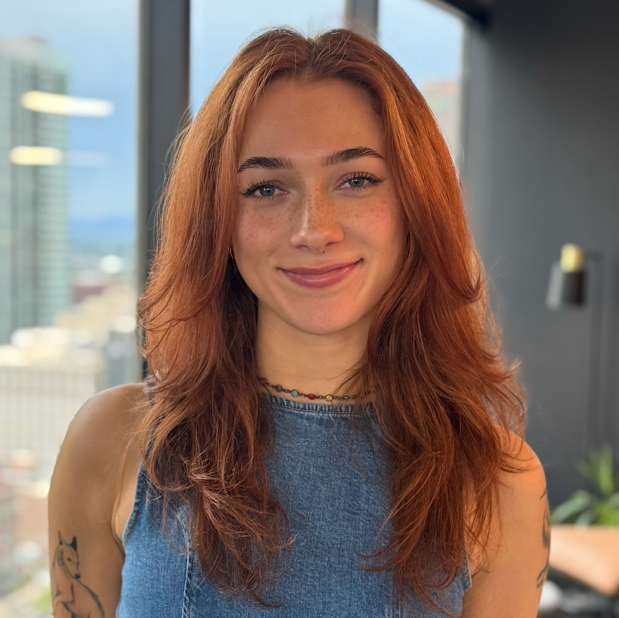 Portrait of a woman with brown hair on a flat gray background.